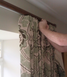 Our expert curtain fitter hanging curtains on a tracked wooden pole